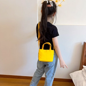Minimalist yellow kids canvas messenger bag shown cross-body on child model back