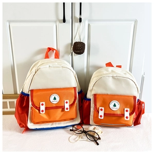 Vue détaillée de deux sacs à dos en toile avec blocs de couleurs et badge Good Luck