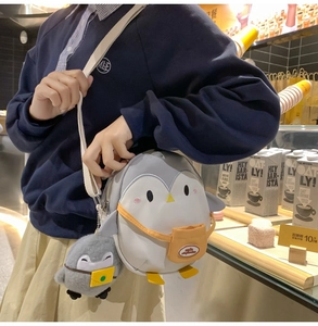 Detail of cute cartoon penguin crossbody bag with plush charm and contrast color design