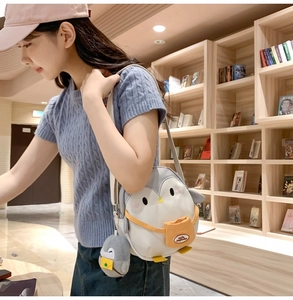 Cute penguin cartoon crossbody bag for kids with mini pendant shown in a library setting