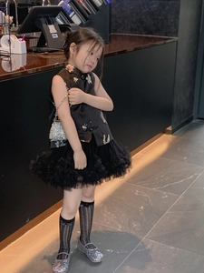 Detail of a girl wearing a black traditional silk vest with embroidery and a tulle skirt