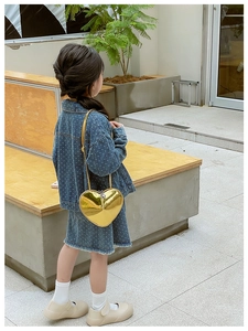 Sac à bandoulière tendance en forme de cœur doré brillant porté par un mannequin