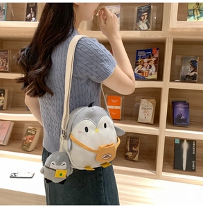 Detail view of a cute penguin crossbody bag with creative patchwork and small yellow pocket