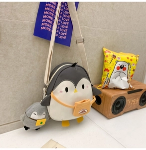 Detail view of penguin crossbody bag featuring yellow feet and matching plush pendant