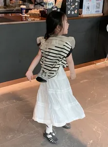Dettaglio bambina con t-shirt a righe, fiocco in tulle e gonna di pizzo bianco