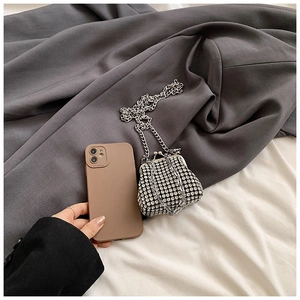 Detail of mini rhinestone clutch bag with silver chain next to a phone for size reference