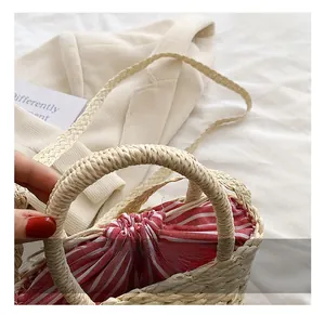 Detail of hand-woven straw bag with red striped drawstring lining and round handle