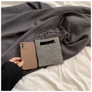 Detailed close-up of a silver rhinestone mini bag with a fine chain next to a phone
