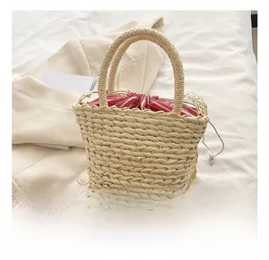 Detail of straw bucket bag with red striped drawstring lining and woven handles