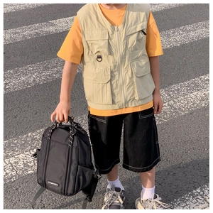 Detailansicht der Kinder Khaki Weste mit orangefarbenem T-Shirt und Mode-Rucksack