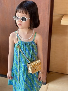Detail of a kids gold quilted crossbody bag with pearl sunglasses and a floral dress