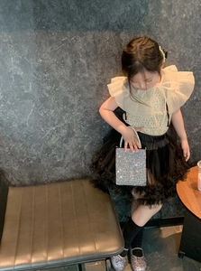 Detail of girl wearing ruffled top, tutu skirt and luxury rhinestone chain handbag