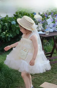 Detail of child girl cream tulle dress with mini pearl bag and straw hat set