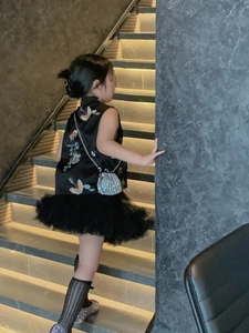 Detail of child wearing a modern black qipao top with colorful butterfly embroidery