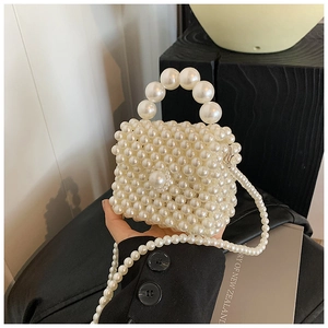 Detail of handmade cream pearl mini bag featuring a beaded top handle and long crossbody strap