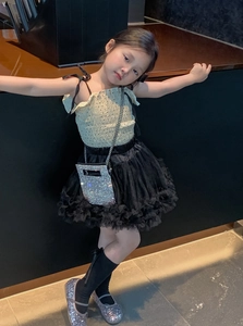 Detail of girl's stylish outfit featuring a sparkling rhinestone bag and layered mesh skirt