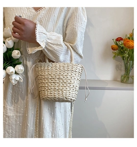 Detail of woven straw bucket bag featuring drawstring closure and top handle for summer