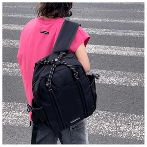 Außenaufnahme des leichten schwarzen Nylon-Schulrucksacks mit Webseil und praktischer Seitentasche