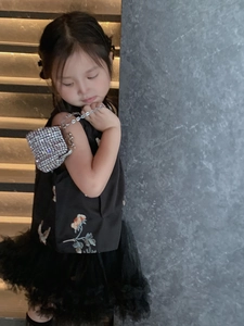Girl carrying a silver rhinestone mini bag with metallic chain and black dress