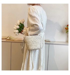 Close-up of lightweight woven straw bucket bag with drawstring closure for summer beach outings