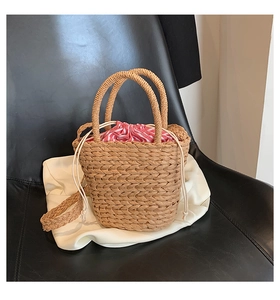 Detail of straw bucket bag featuring red and white striped drawstring and woven handles