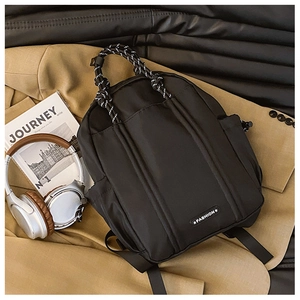 Detail eines schwarzen Nylon-Rucksacks mit gewebten Griffen und Seitentasche