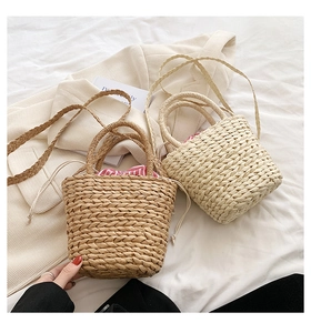 Detail of straw woven bucket bags in brown and beige with striped drawstring lining