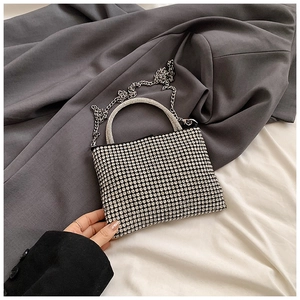 Detailed macro view of silver rhinestone handbag with metallic circular handle and chain