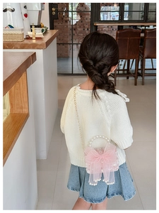 Pink girls crossbody bag with large organza bow and pearl handle shown on a model