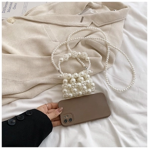 Macro detail of a white pearl beaded mini bag showing woven texture and long shoulder strap
