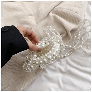 Detail of white handmade pearl beaded mini bag with floral texture and long strap