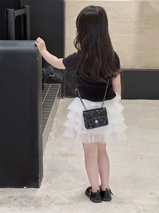 Detail of kids black quilted crossbody bag with metal flower clasp and chain strap