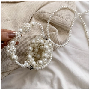 Detailed macro view of woven white faux pearls on a kids crossbody bag with silver clasp