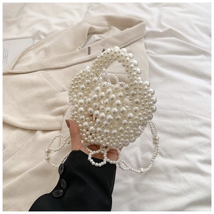 Detail showing the glossy white pearls and fine craftsmanship of the mini handbag