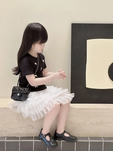 Fashionable girls summer outfit featuring a black bow t-shirt and white tulle layered skirt