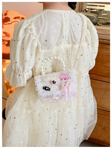 Detailed back view of a pink girls tweed crossbody bag with pearl handle and lace bow