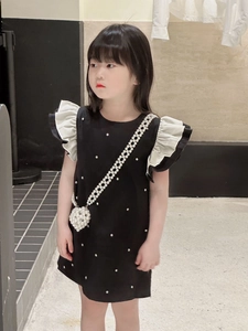 Détail de robe noire pour fille avec manches à volants et sac à perles en forme de cœur