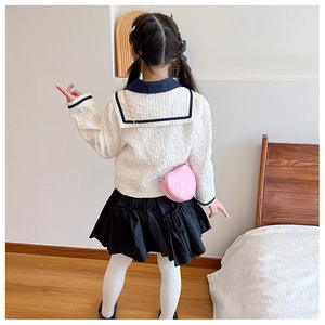 Rear view of girl wearing navy collar jacket with pleated skirt and heart chain bag
