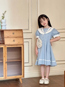 Detailed close-up of a blue girls' princess dress with a white sailor collar and pearl bag