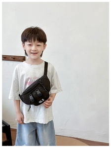 Detail of black nylon kids chest bag featuring dual buckle pockets and white IOLB letters