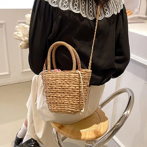 Handmade woven straw bucket bag for summer travel featuring a red striped fabric liner