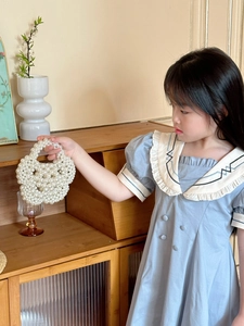 Detailed close-up of a white handmade pearl beaded handbag for kids in a home setting