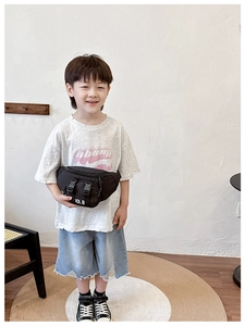Detail of a black canvas kids chest bag with dual buckles and 10L B print on a child