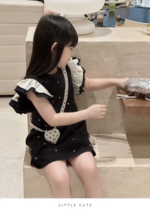 Détail d'une robe noire pour fille avec manches à volants et sac perle en forme de cœur