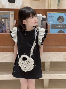Detail of white pearl heart-shaped crossbody bag on a girl's black dress