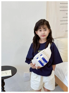 Detail of kids chest bag in cream canvas with blue strap and double zipper pockets