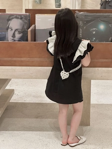 Détail d'un mini sac en perles en forme de cœur sur une robe noire pour fille