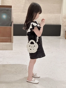Elegant white pearl beaded handbag for girls styled with a black dress in a modern room