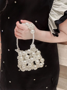 Detailed view of hand-woven white pearl handbag with beaded texture and elegant handle