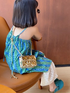 Close-up of kids gold quilted shoulder bag with chain strap and metallic lock detail